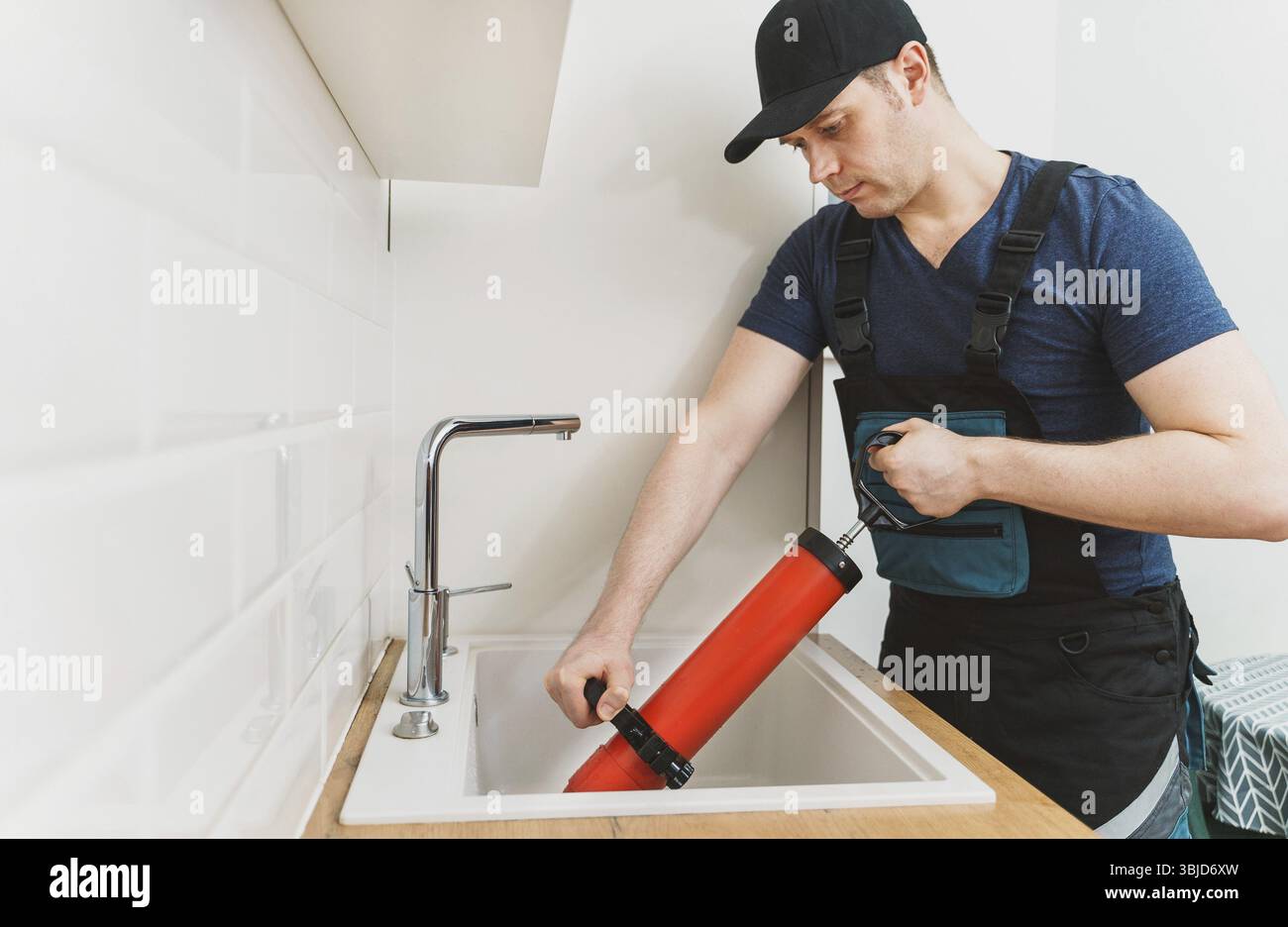 Plumber unclogging kitchen sink with professional force pump cleaner Stock Photo
