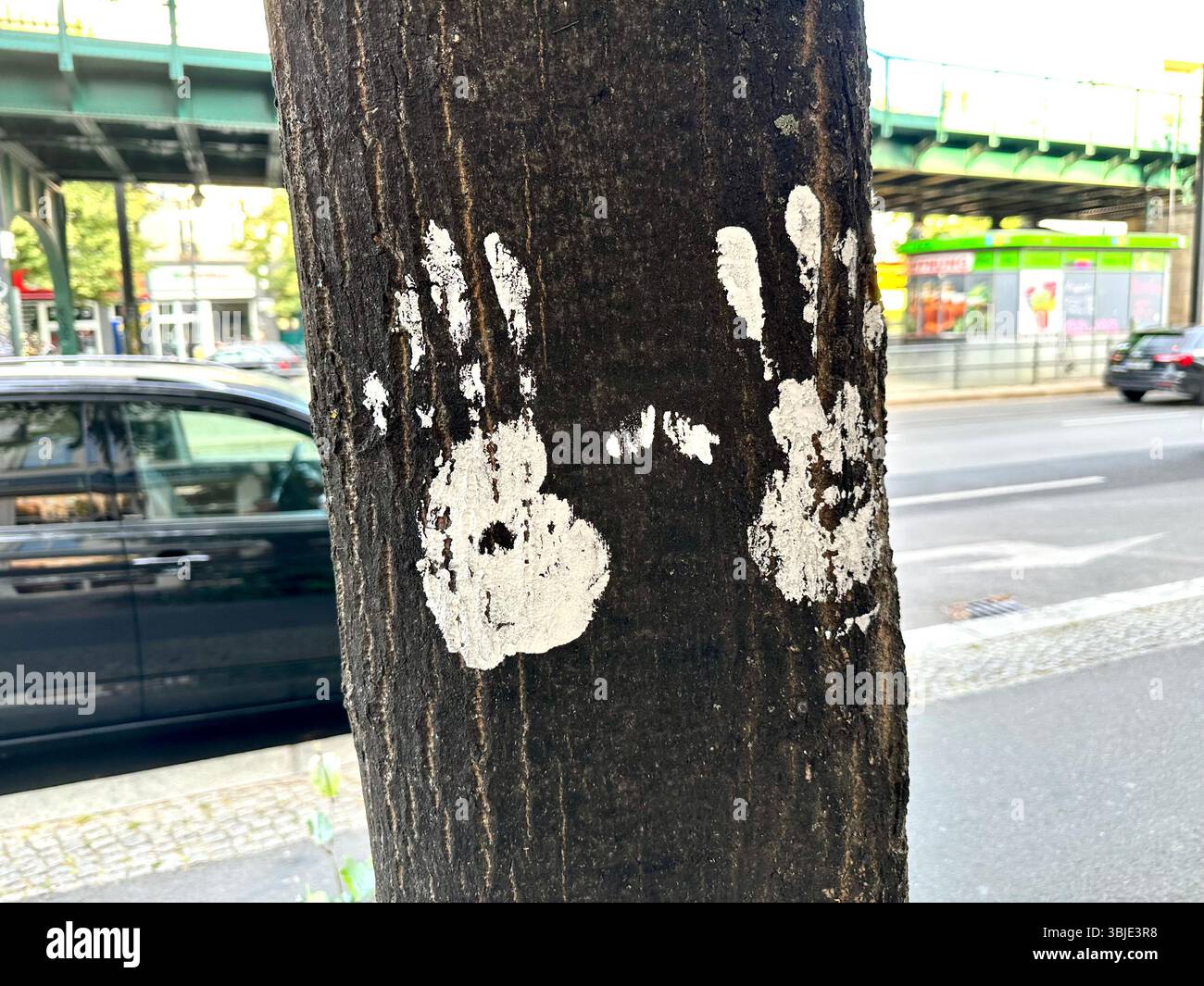 Two white hand prints on a tree in Berlin, Germany, with a street in the background - Smartphone Captured Stock Image