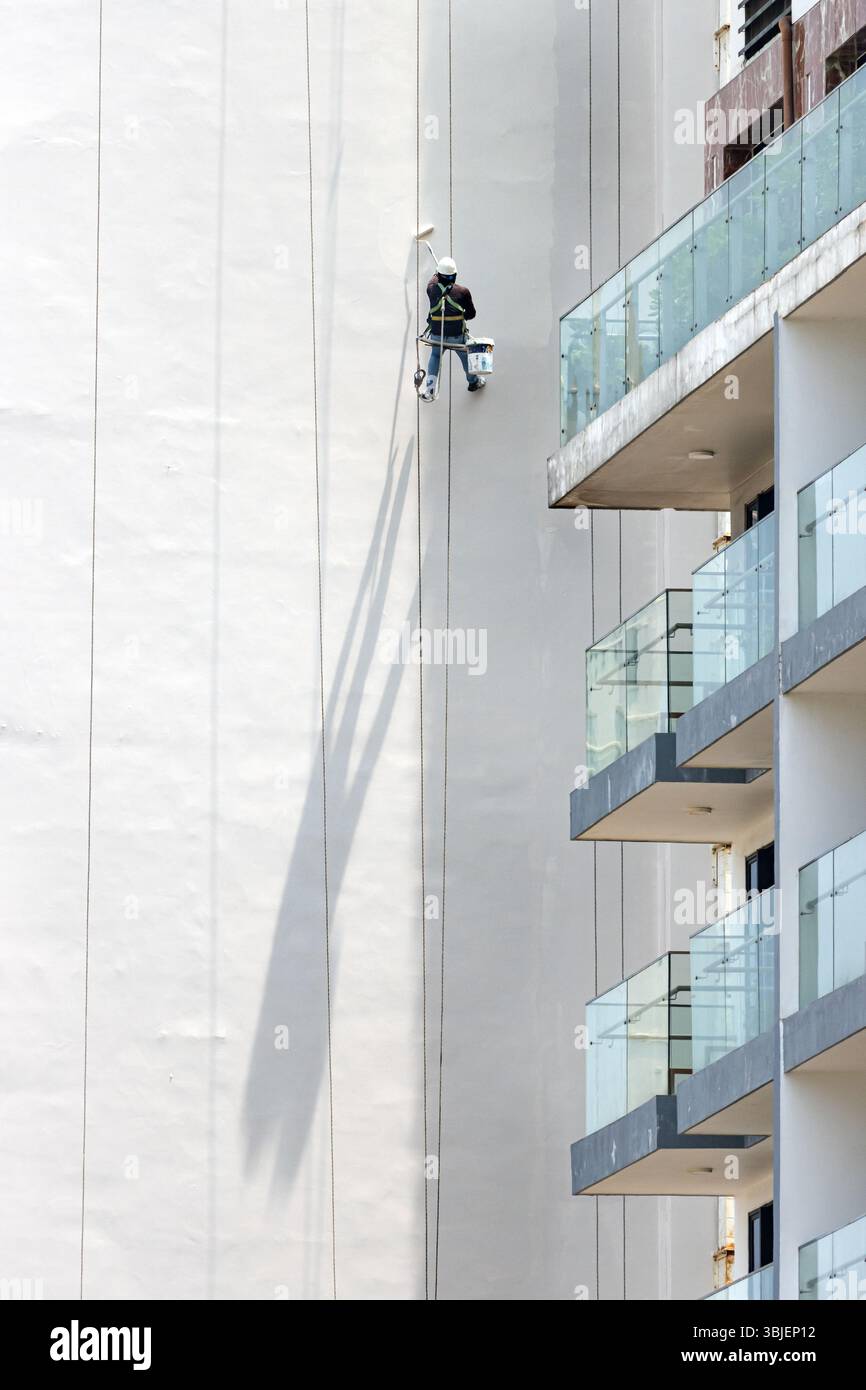 A professional worker paints the tall exterior wall of a building with ...