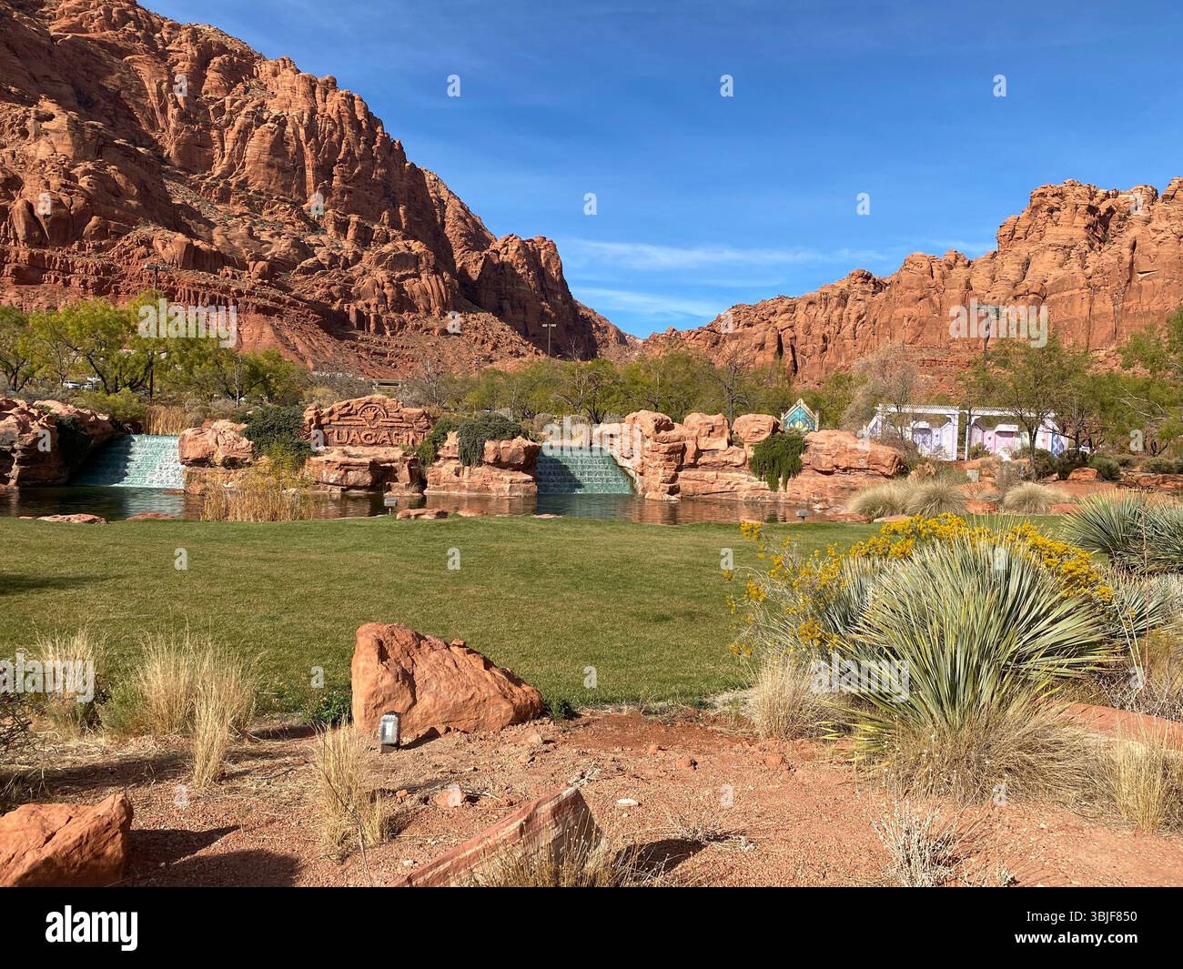Striking landscape featuring contrast between natural rock formations and a man-made, landscaped area. In the background, towering red rock mountains. - Smartphone Captured Stock Image