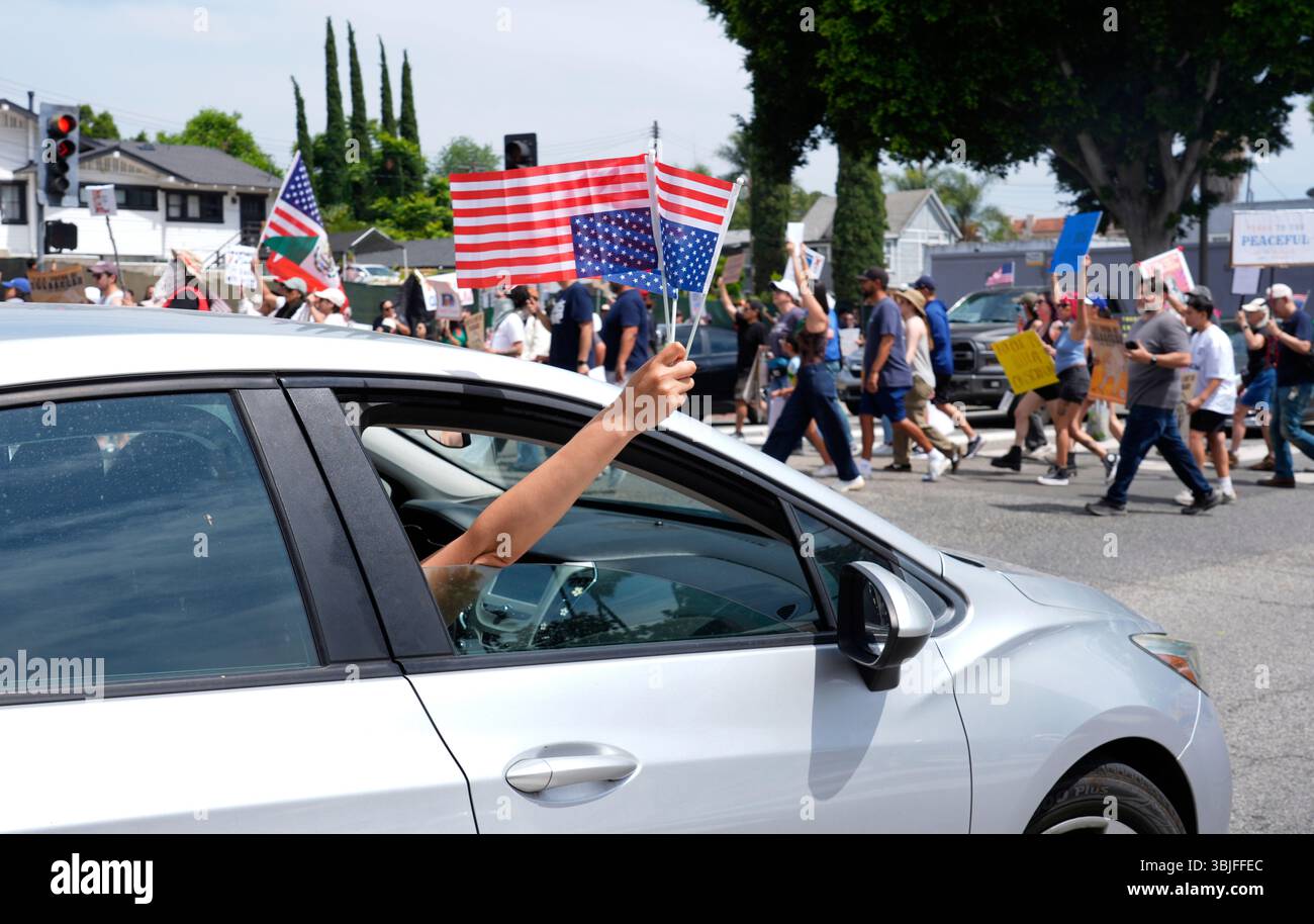 American flags are waved outside a car window during a