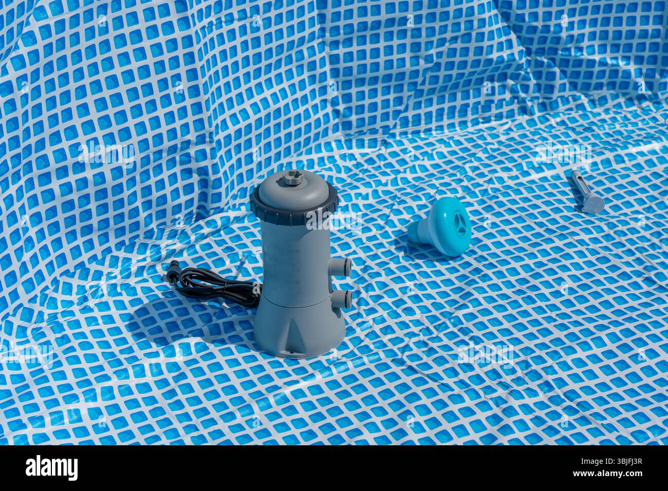 Setting up a pool with pump and accessories on a blue and white ...