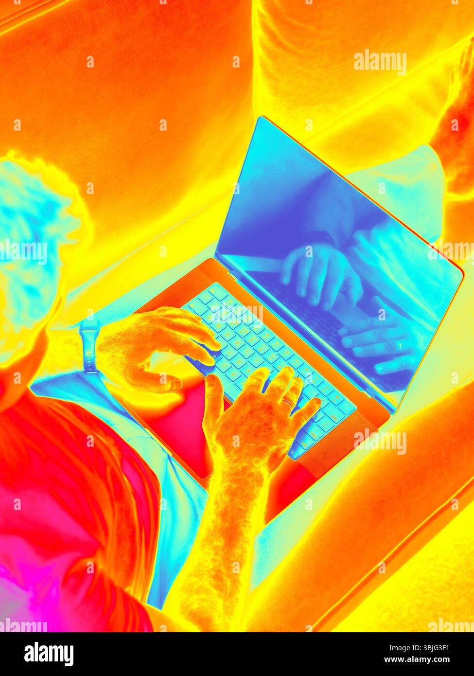 Infrared Thermal image of man typing laptop on modern sofa. Ideal for remote work, home office, freelance, and digital lifestyle. Male hands typing on laptop Stock Photo