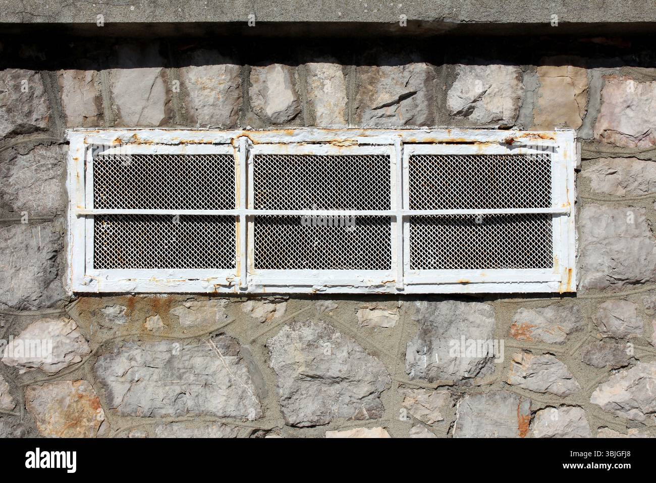 Rust Metal Window A rectangular window with a rusted metal grille and mesh is set in a ...