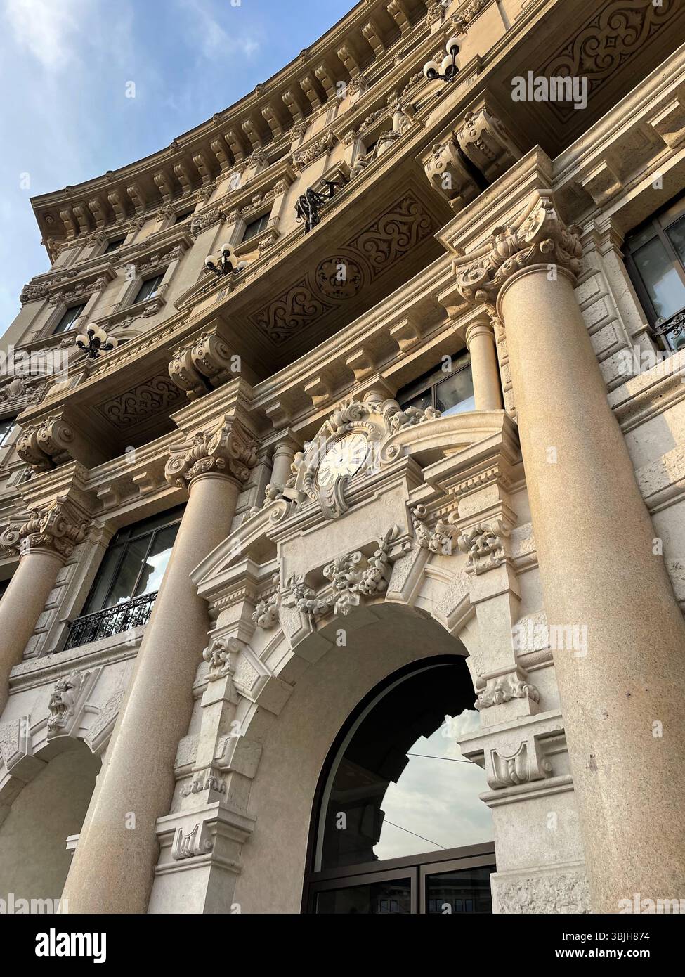 Ornate Historic Building Facade with Columns and Clock in Milan, Italy - Smartphone Captured Stock Image