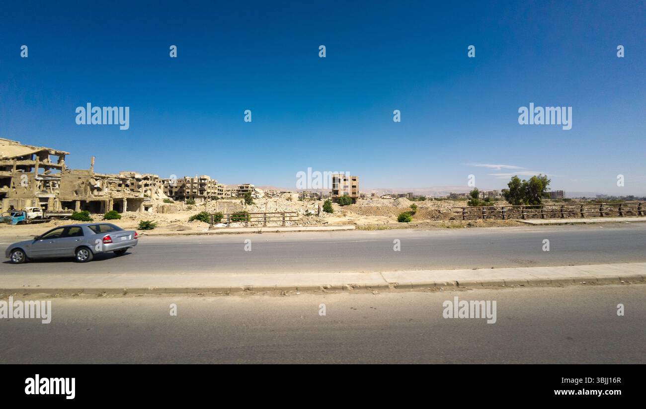 Abandoned, war-torn cityscape with damaged buildings under a clear blue ...
