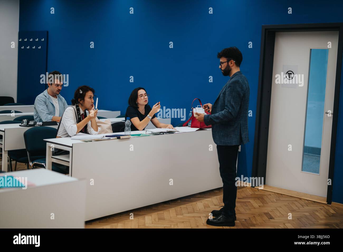 Professor assisting students during classroom session in university Stock Photo