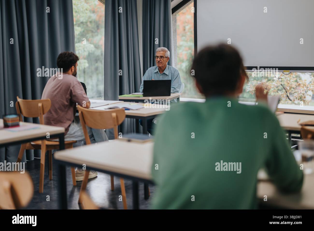 Students engaging with experienced professor in modern classroom setting Stock Photo