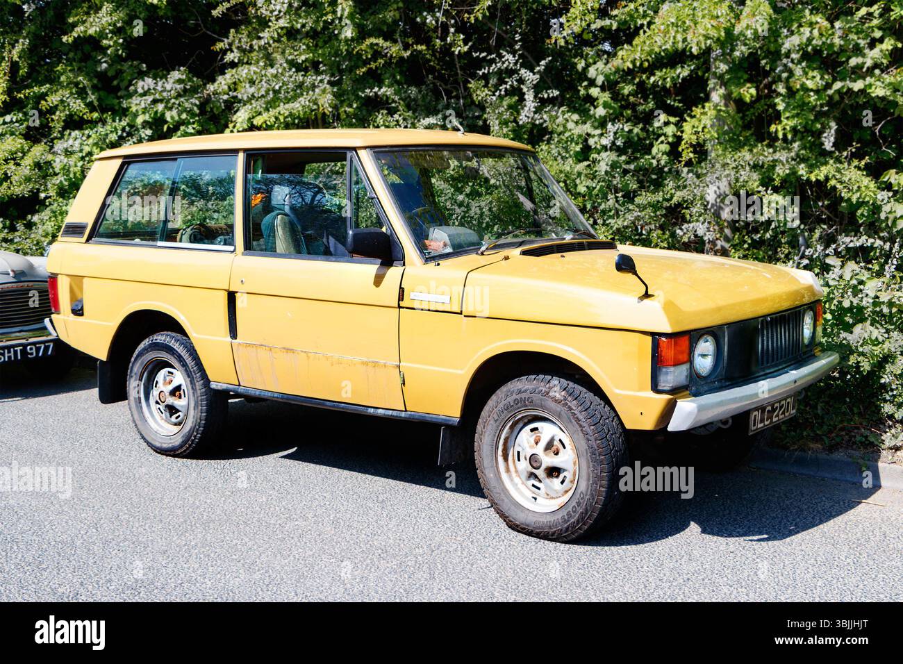 Vintage 1970s yellow range rover SUV parked on a sunny street with ...