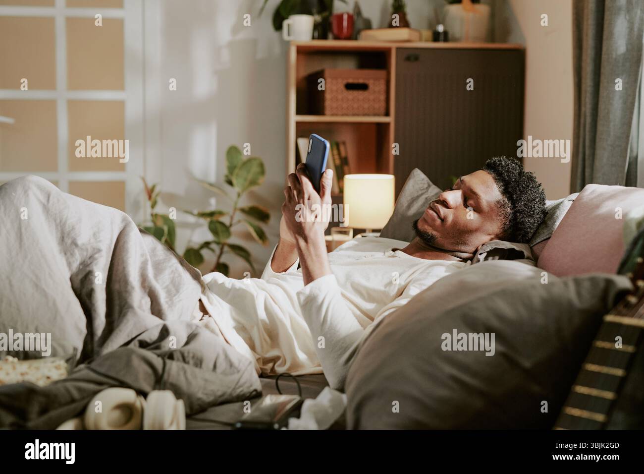 Relaxing in Bed While Using Smartphone on Cozy Evening Stock Photo