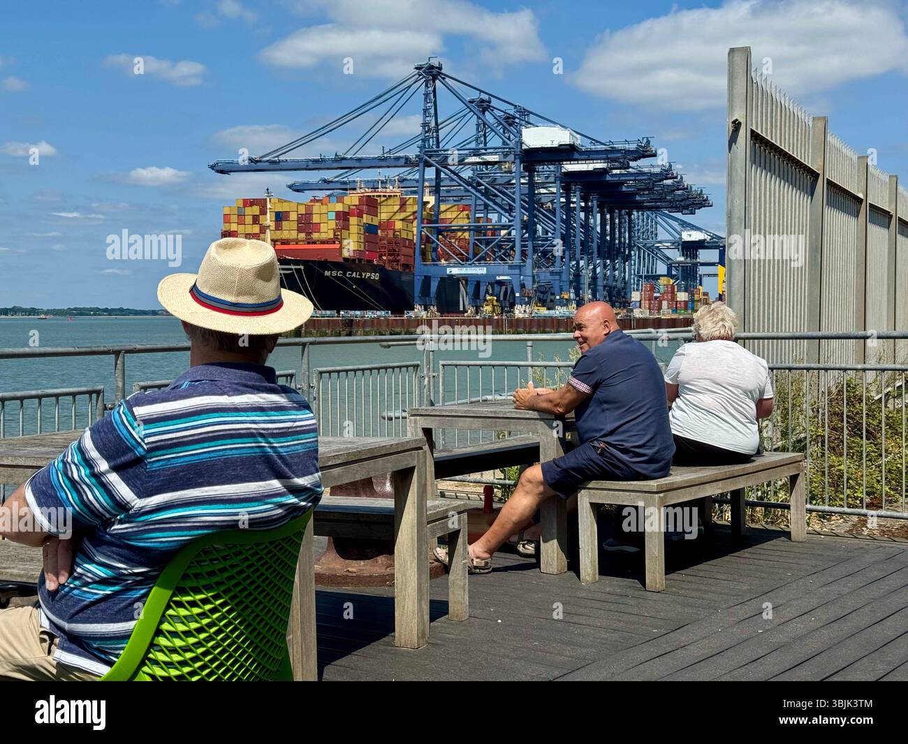 Felixstowe, Suffolk - 16 June 2025 : Hot summer afternoon.Three people on the deck of the Viewpoint cafe looking towards the port. - Smartphone Captured Stock Image