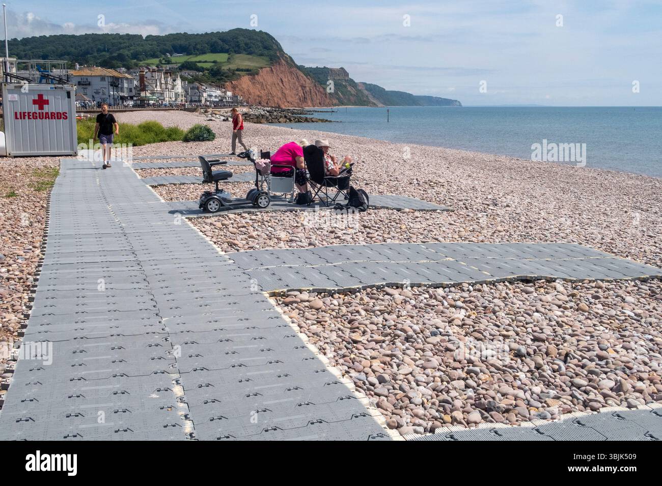 Accessible matting at Sidmouth Beach allows mobility scooters, wheelchairs and mums with pushchairs to enjoy the glorious weather. Stock Photo