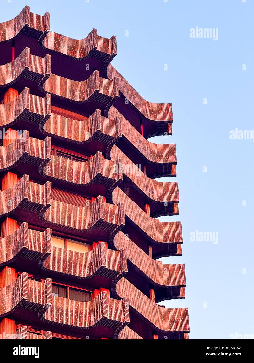 Striking photo of a contemporary high-rise featuring bold, curved brick ...