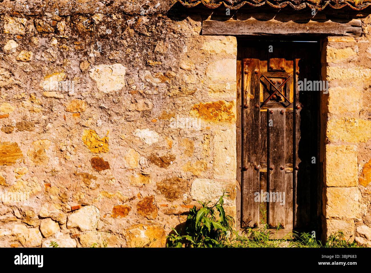 Stone facade with old wooden door. Pedraza, Segovia, Castilla y León, Spain, Europe Stock Photo