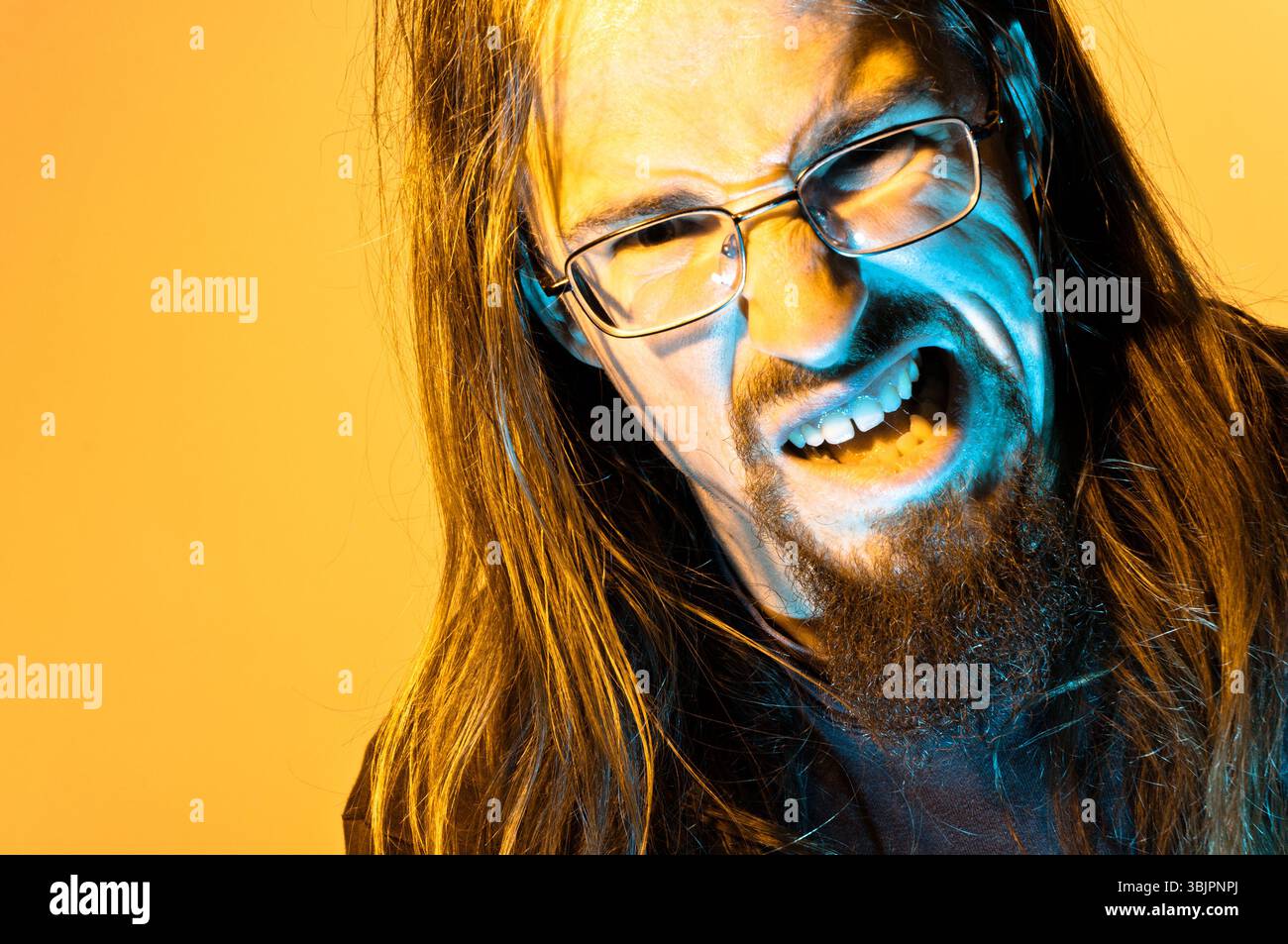 Insane mad man against yellow background yelling Stock Photo
