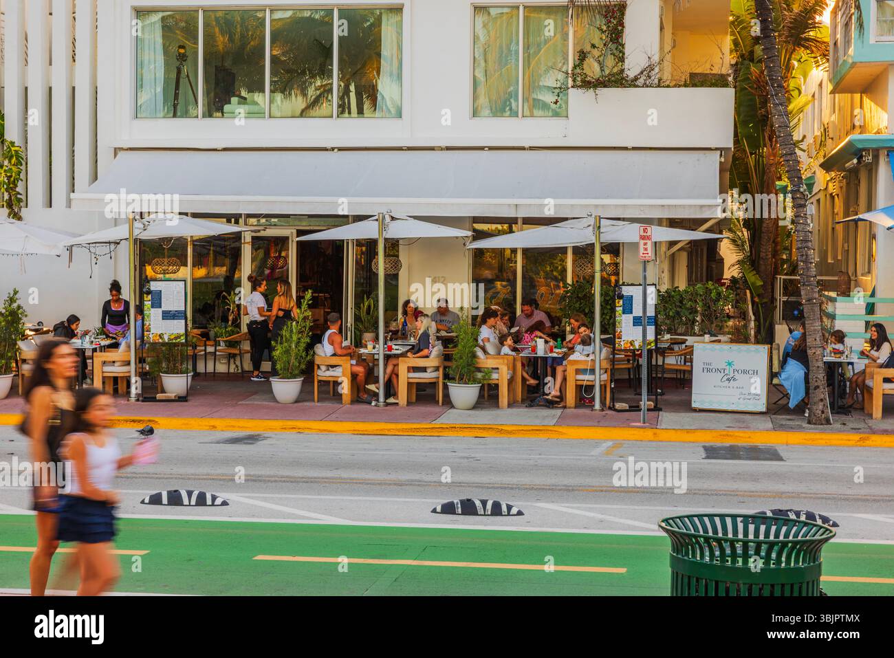 Outdoor diners at The Front Porch Cafe on Ocean Drive in Miami Beach during warm evening with palm shadows. Miami Beach. USA. Stock Photo