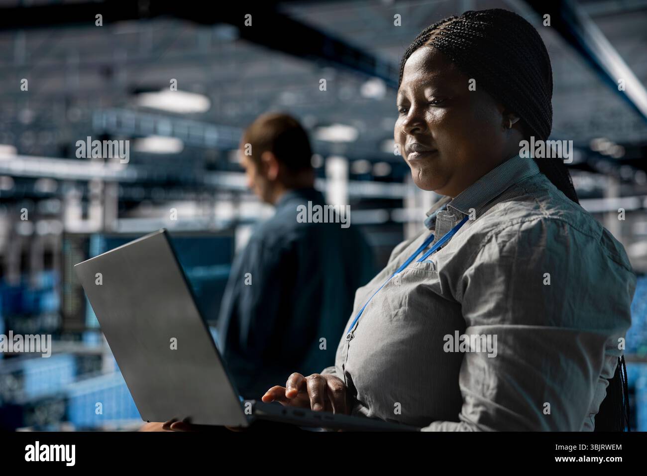 Teamworking data center programmers writing code for resource optimization using notebook. Server farm coworkers in data center refining algorithms for faster processing using laptop Stock Photo
