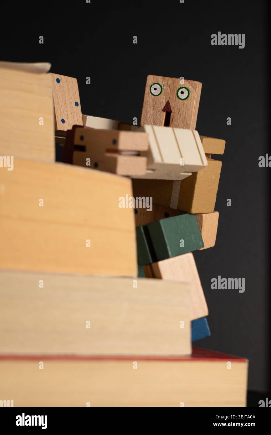 Wooden robot climbing stack of books for personal growth Stock Photo