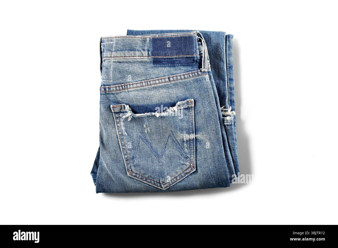 Light-washed ripped denim jeans folded flat on white surface Stock Photo