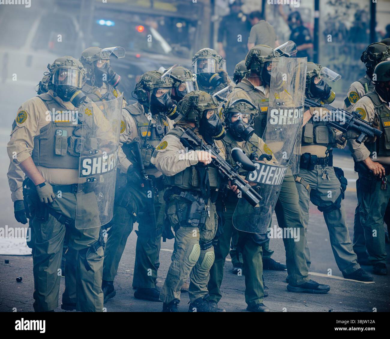 Sheriff's deputies advance through a cloud of smoke during a ...