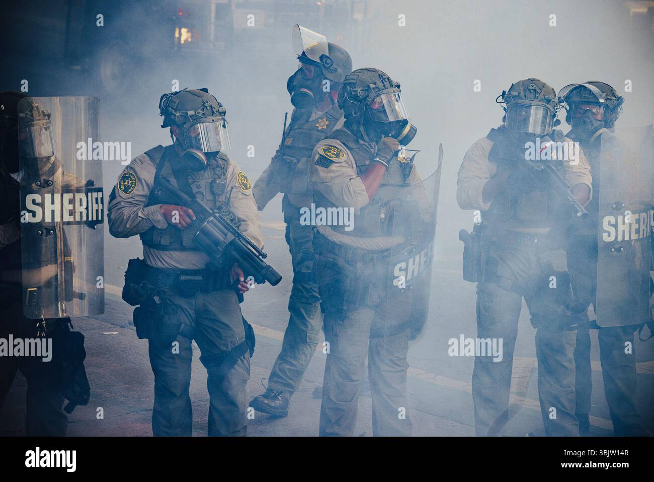 Sheriff's deputies advance through a cloud of smoke during a ...