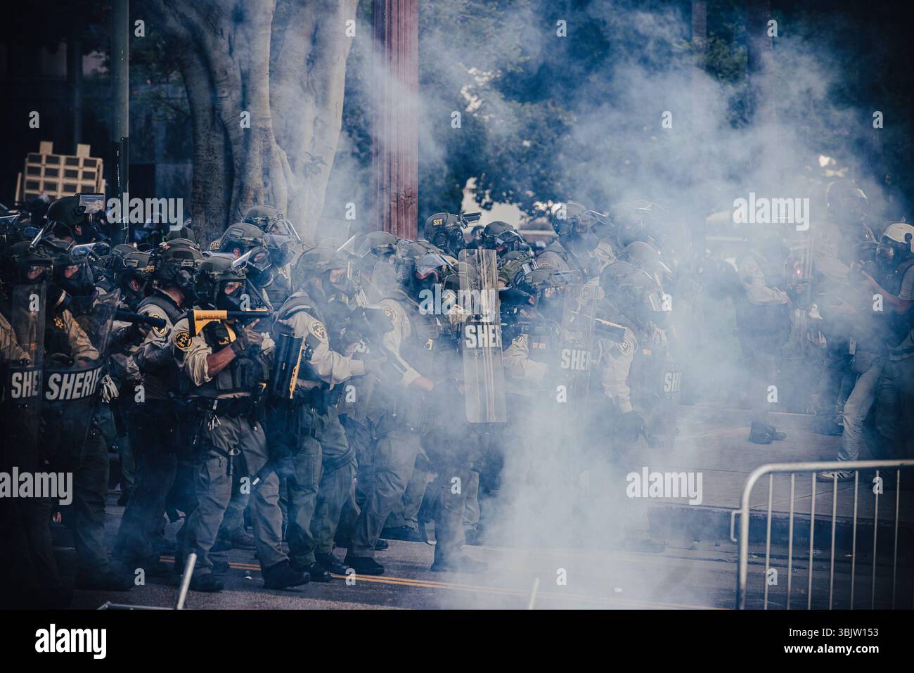 Sheriff's deputies advance through a cloud of smoke during a ...