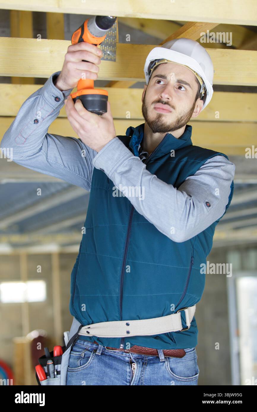 mature carpenter drilling wood Stock Photo