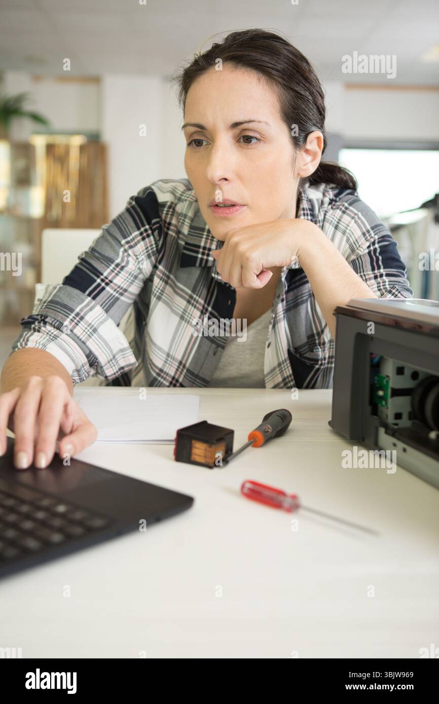 serious woman fixing a printer Stock Photo
