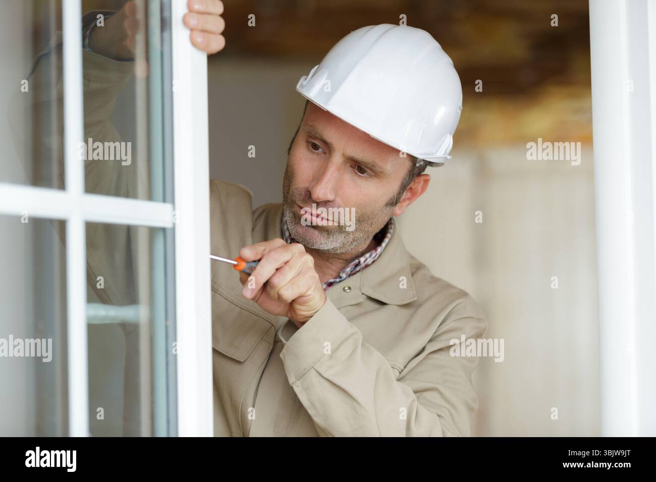 young repairman fixing window frame in room Stock Photo