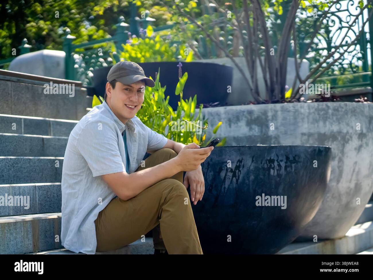 A young happy man talks, communicates on a smart phone outdoors. Stock Photo