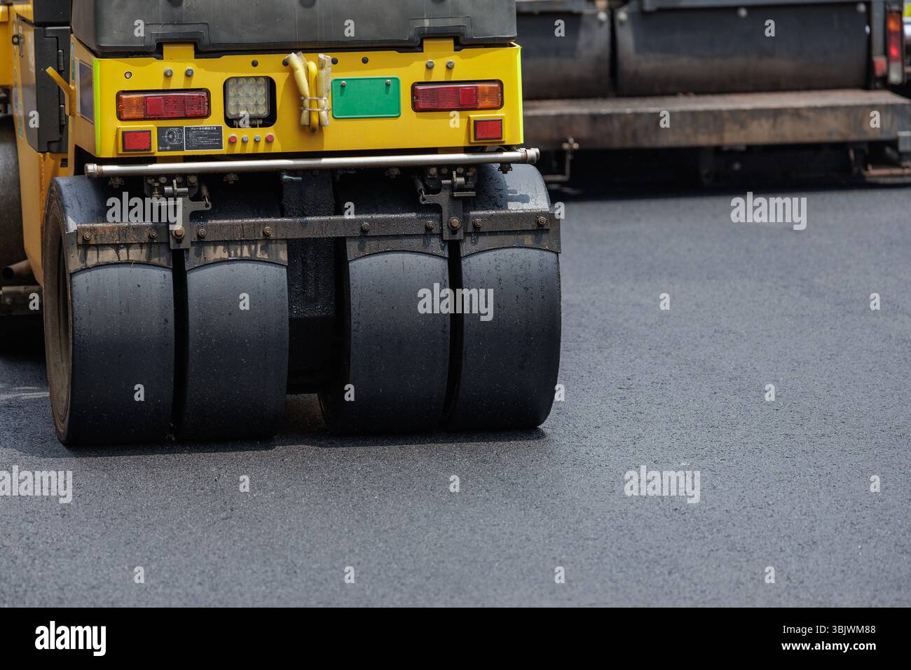 Asphalt Rool Work Heavy-duty yellow asphalt roller compacts freshly laid, hot asphalt ...