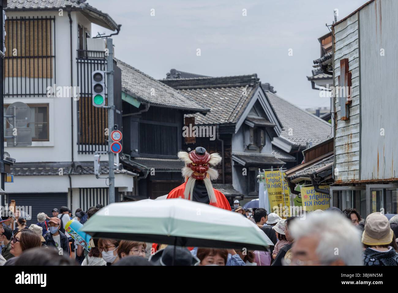 Performer wearing traditional Japanese Oni mask is focus on crowded street during annual Japanese festival for Arimatsu-shibori, or resist-dyeing. Stock Photo