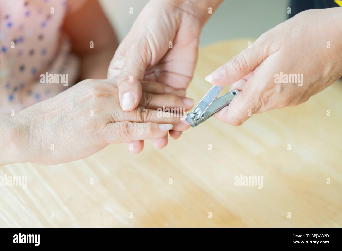Close-up of the fingernails of two unrecognizable women. Manicure cutting on the older woman's nails on the table at home. Helping support to elder pe Stock Photo