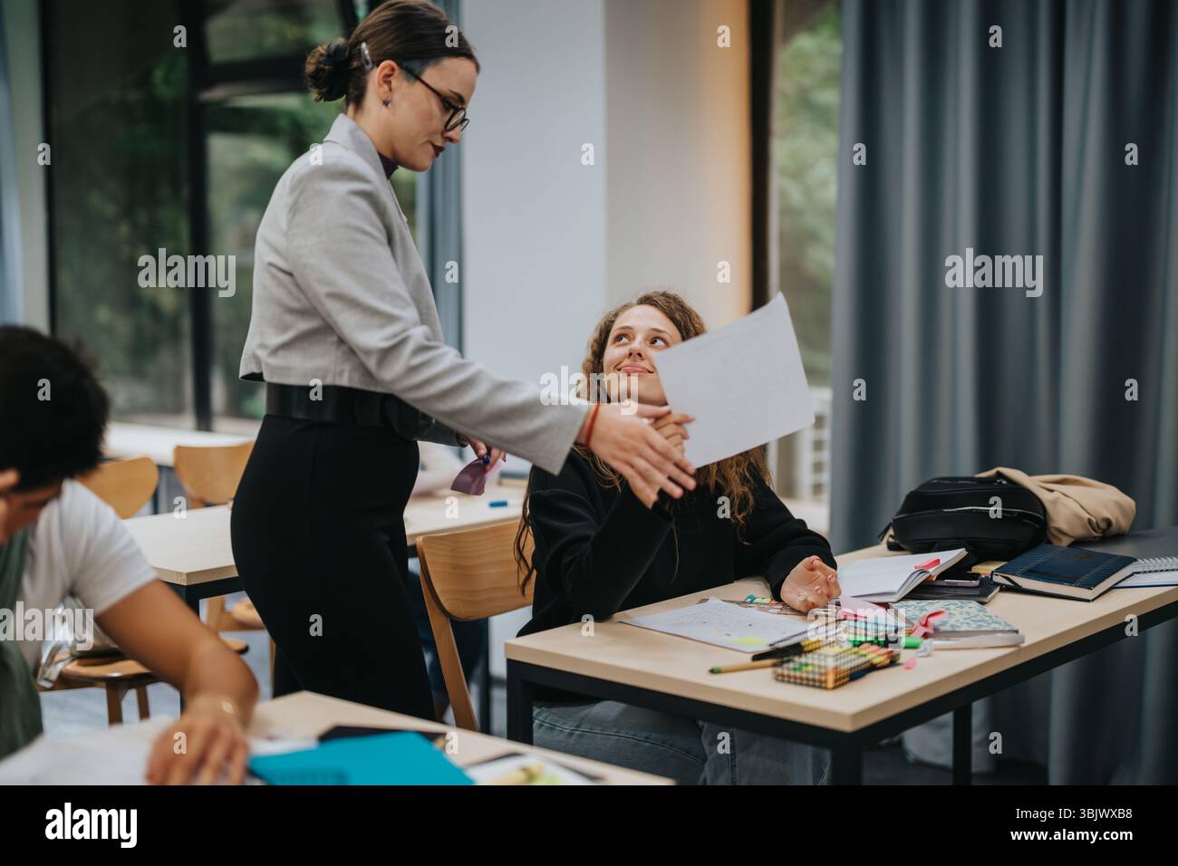 Teacher interacting with students in a modern classroom setting Stock Photo