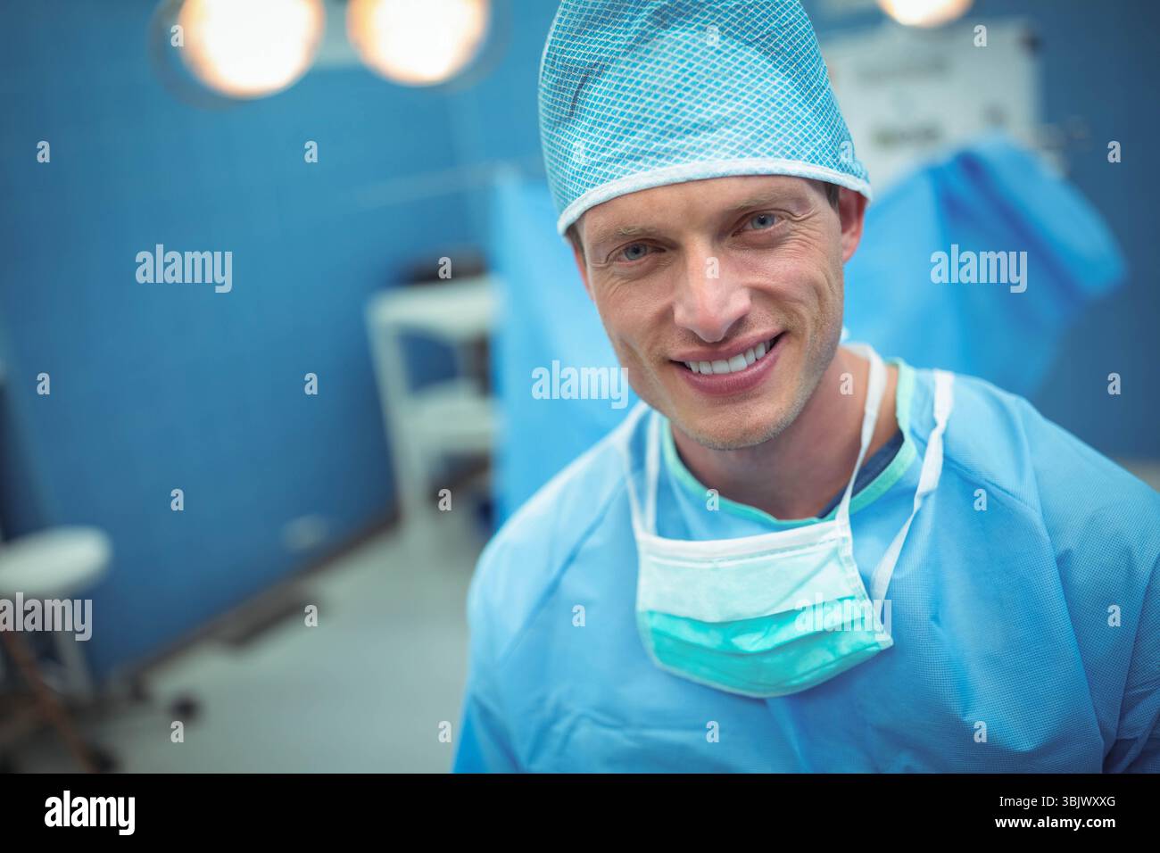 Male surgeon standing in operating room with surgical lights wearing ...