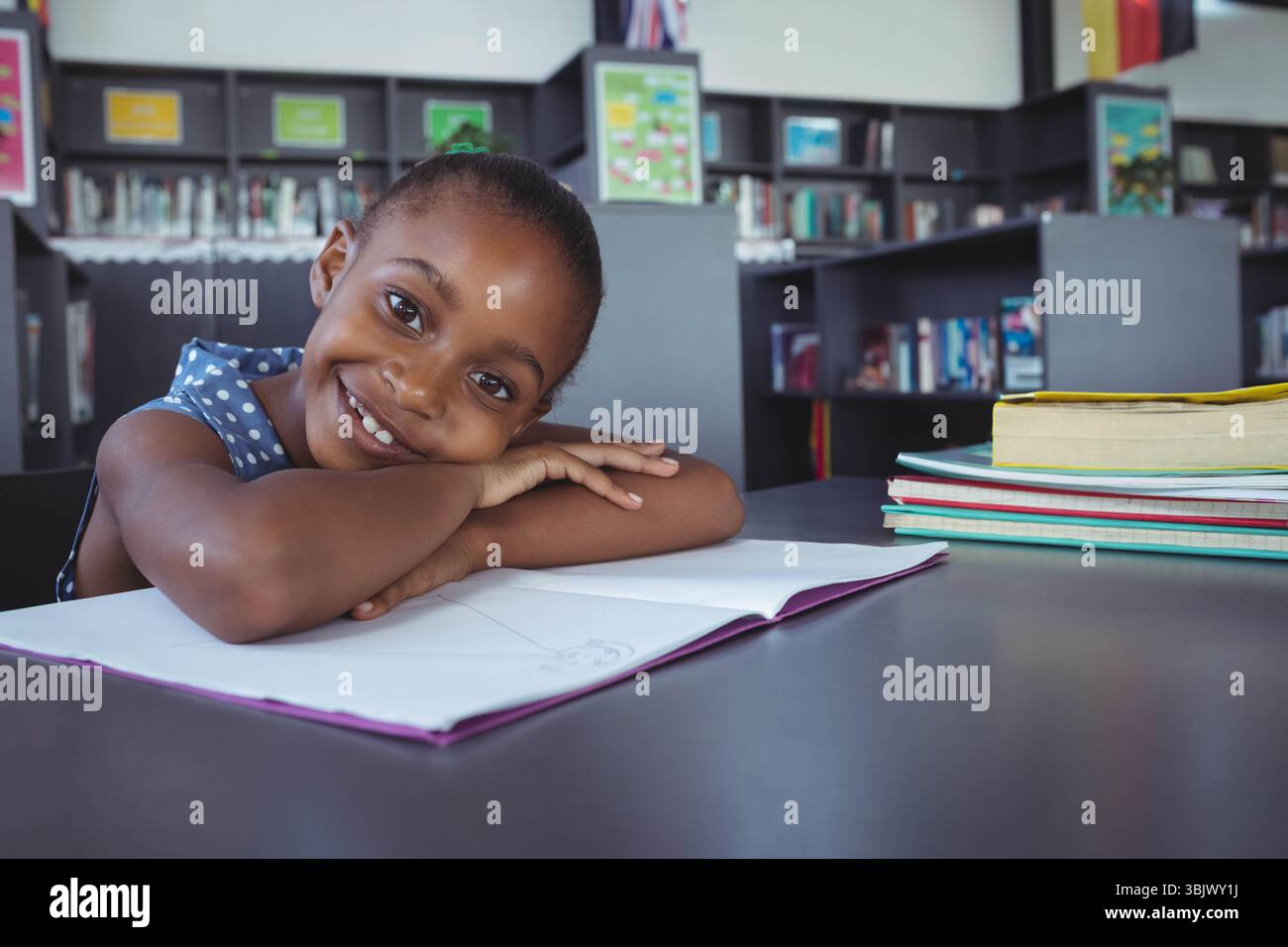 African American girl leaning on table in library studying with ...