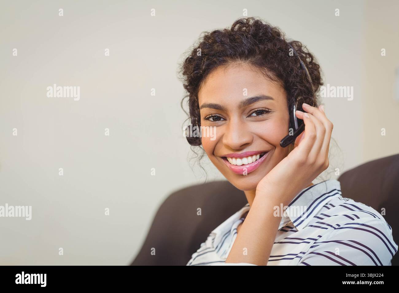Female service rep sitting on office chair in cubicle using headset mic ...