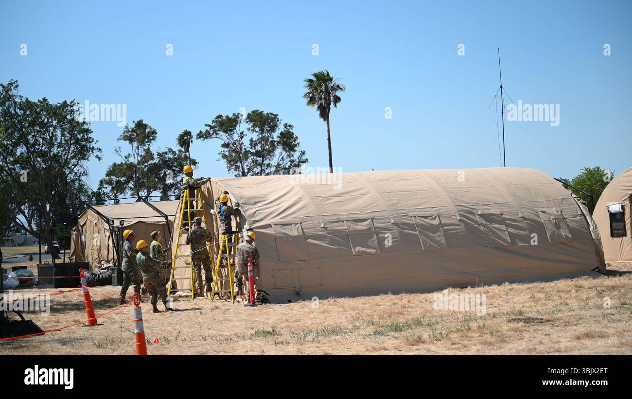 Airmen from the 349th Civil Engineer Squadron (CES) on ladders secure ...