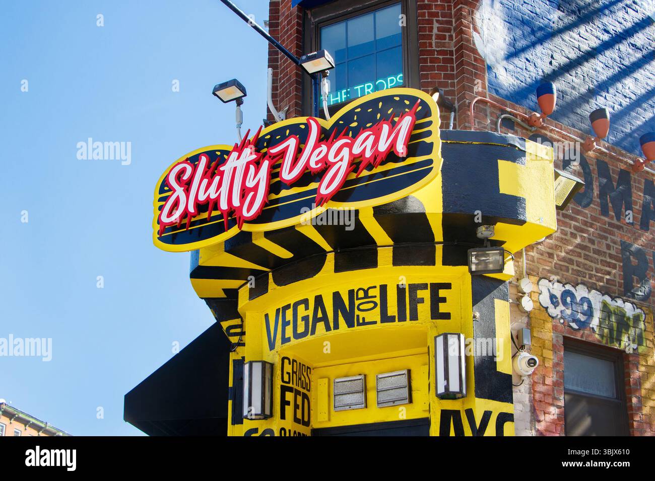 Street view of a vibrant vegan restaurant slutty vegan with a bold neon sign and colorful design on a sunny day in an urban setting Brooklyn nyc Stock Photo