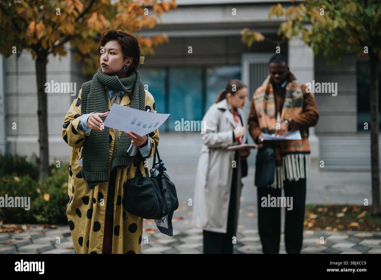 Multiracial team collaborating and analyzing business documents outdoors on a fall day Stock Photo