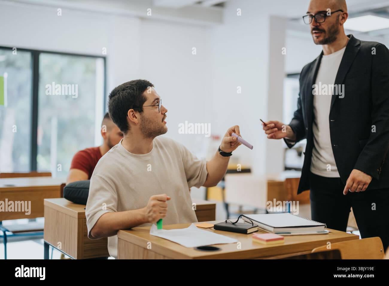 Teacher assisting high school student during classroom activity Stock Photo