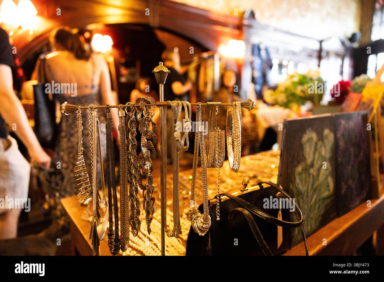 Indoor vintage market with a stall selling jewellery mainly necklaces glinting on a stand, in north London, June 2025 Stock Photo