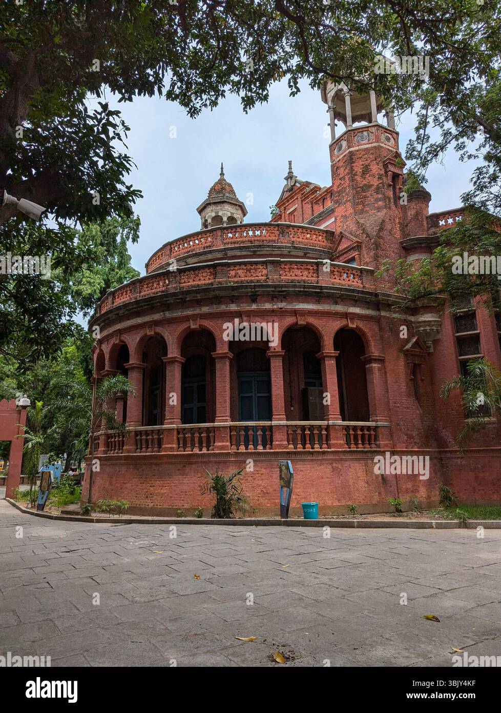 Old walls, tall windows, quiet stories. Red brick wrapped in green — where time stands with grace, and history lingers in every corner. - Smartphone Captured Stock Image
