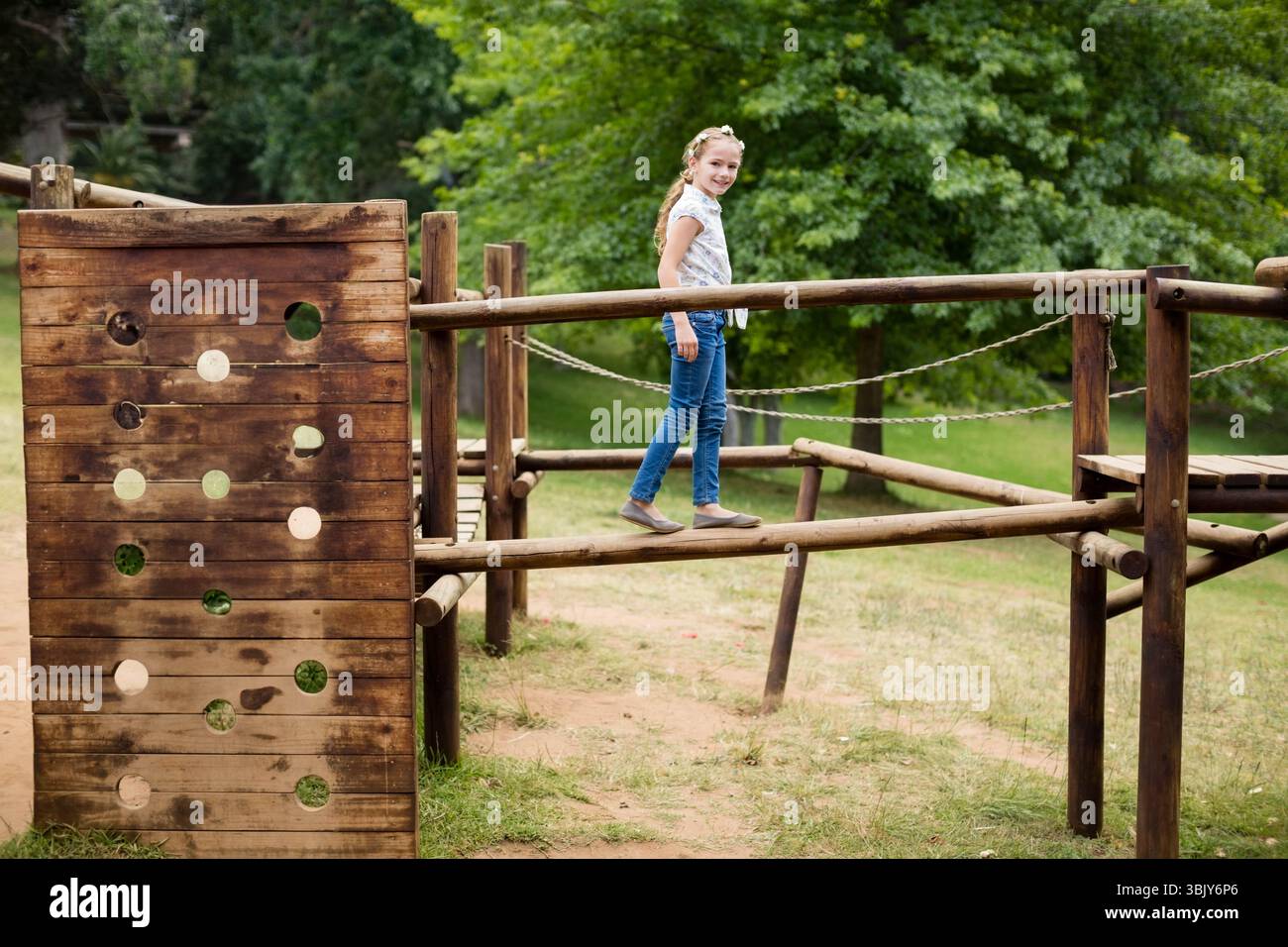 Female child balancing along wooden beam on park playground obstacle ...
