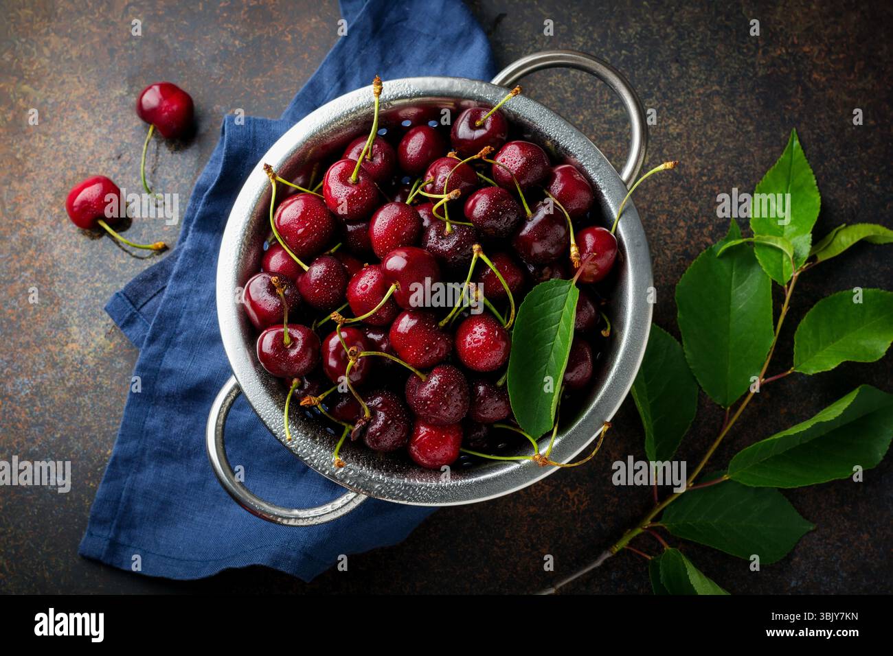 Fresh cherry in iron bowl on a dark concrete background for a pie. Selective focus. Top view Stock Photo