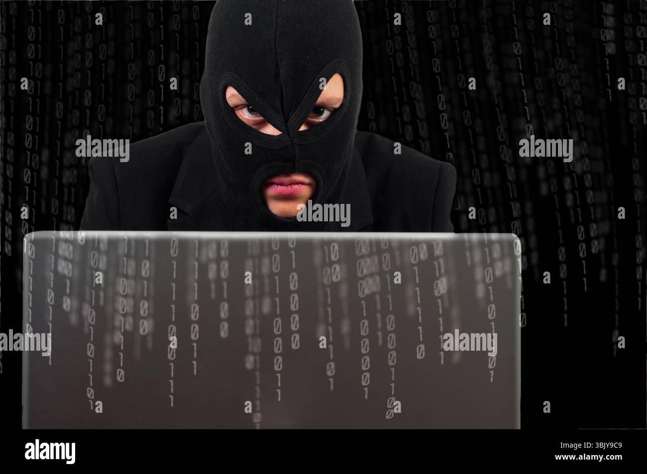 A hacker with a laptop against binary background Stock Photo