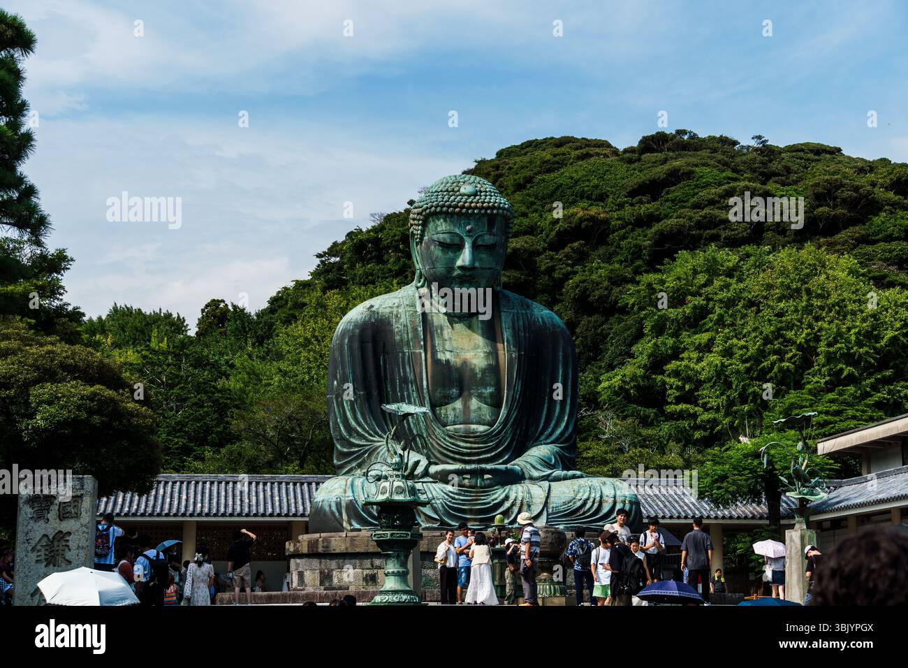 The iconic Great Buddha of Kamakura stands tall as visitors admire the landmark in Japan. Stock Photo