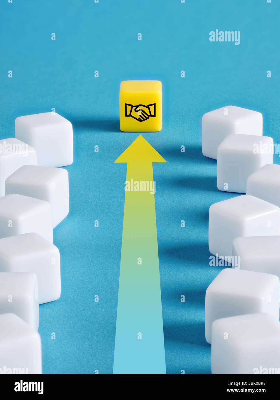Business deal, agreement, partnership and negotiation. Yellow cube with a handshake symbol is leading a group of white cubes on a blue background. Stock Photo