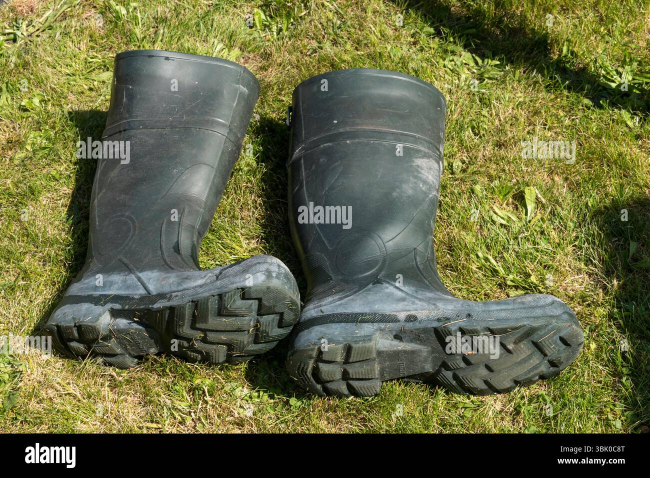 Rubber Wellington boots laid on grass surface Stock Photo