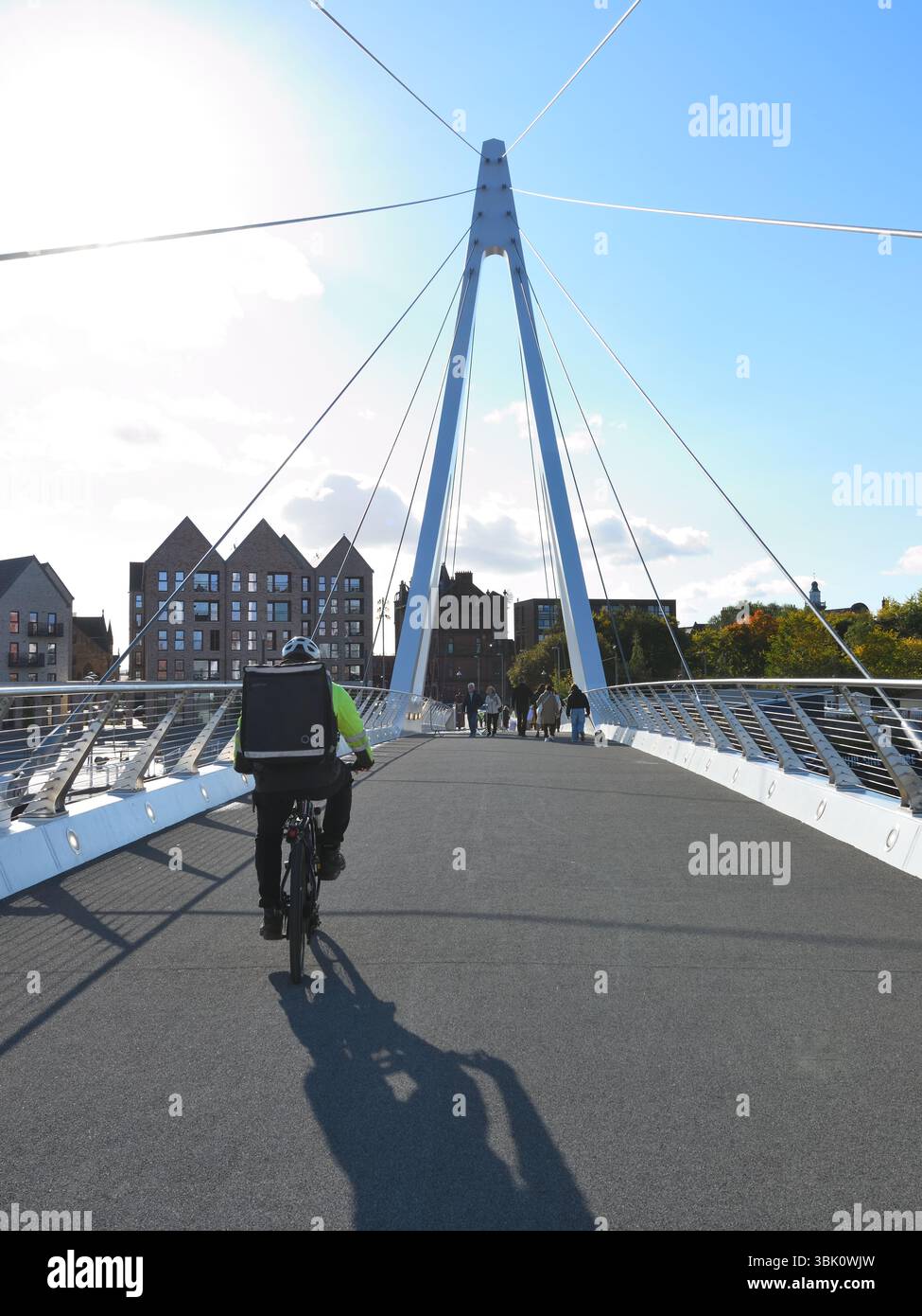 A fast food delivery cyclist with Boolanga bag making use of the new Partick - Govan pedestrian swing bridge in Glasgow, Scotland Stock Photo